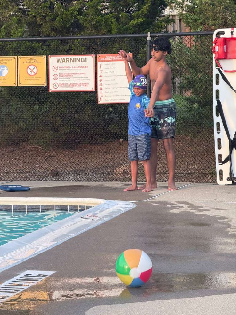Rehan showing a young student the streamline position beside the pool