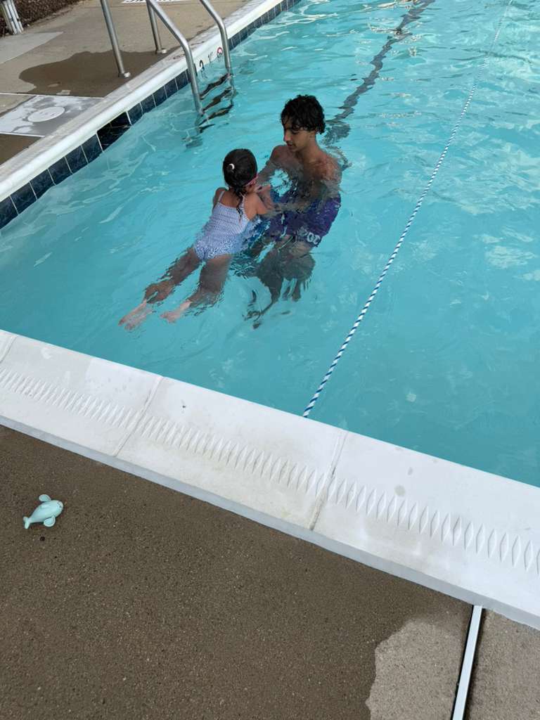 Rehan teaching a young swimmer to float in the pool